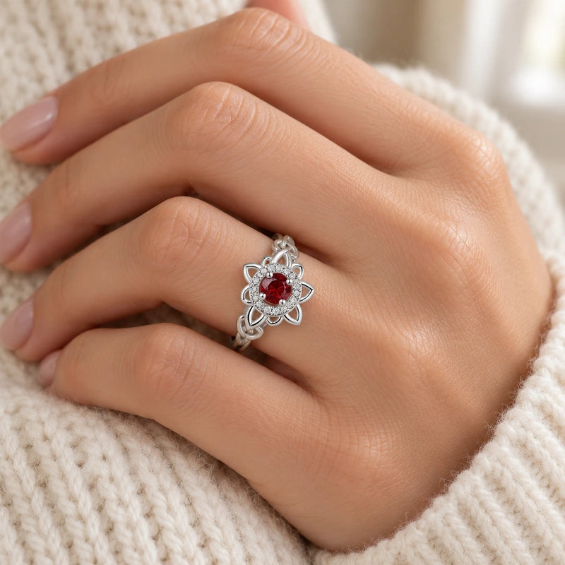 Garnet-red Celtic floral ring worn on an adult hand